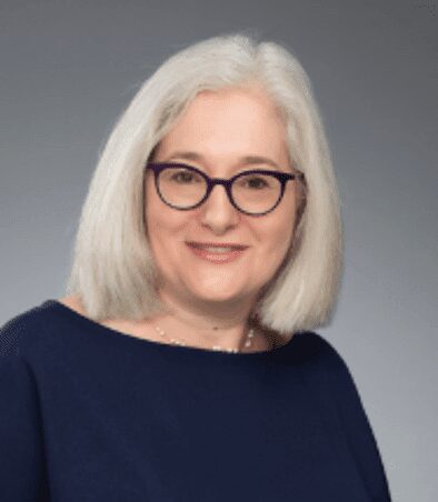 Smiling woman with white hair and purple glasses